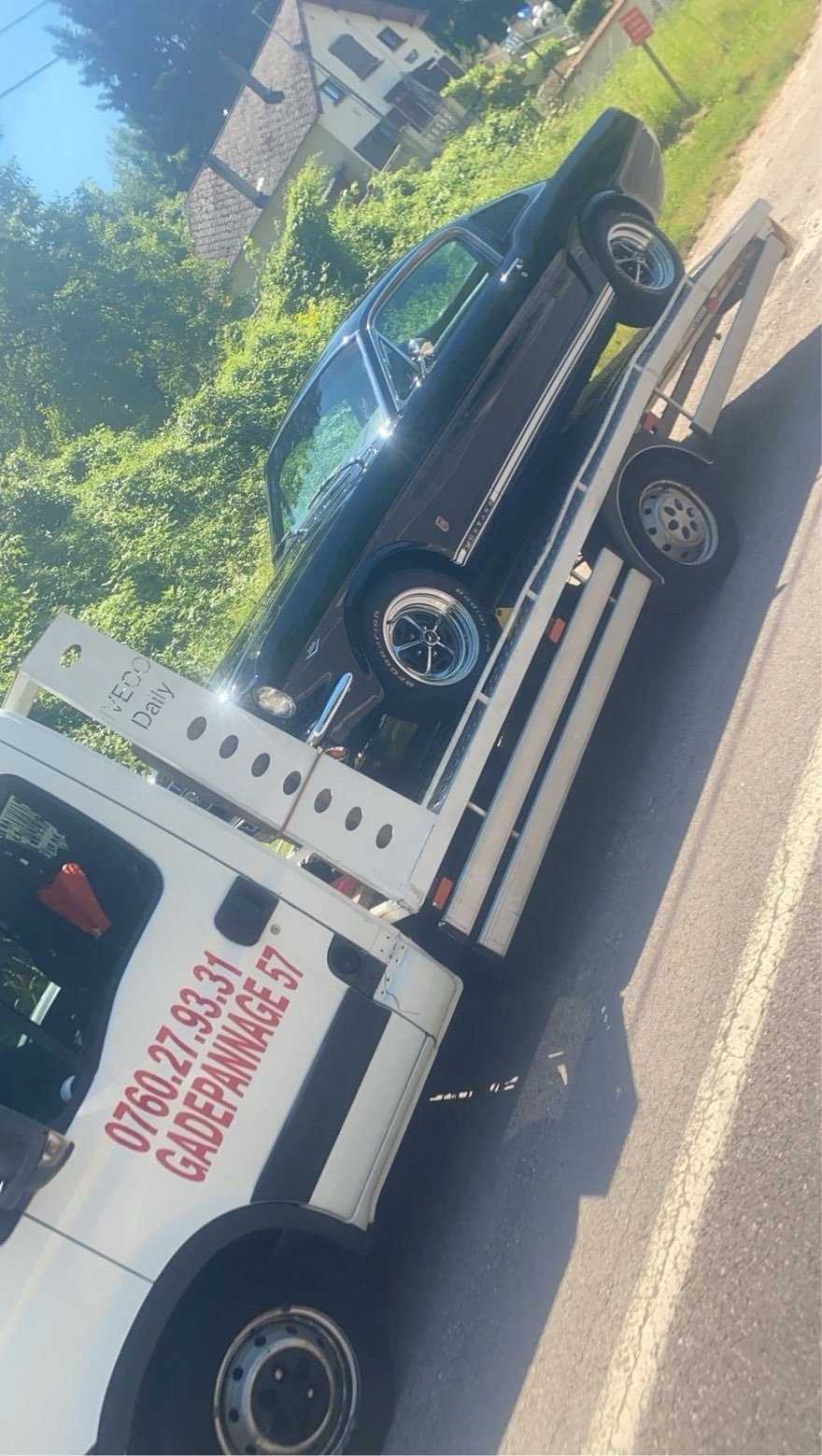Voiture ancienne noire arrimée sur une dépanneuse plateau GA Dépannage